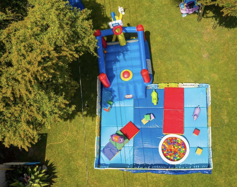 A colorful inflatable playground with various obstacles and a ball pit on grass.