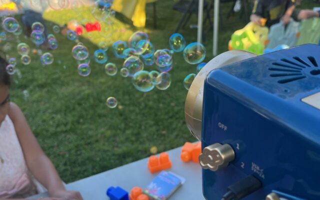 Children playing with bubbles and colorful toys at an outdoor event.