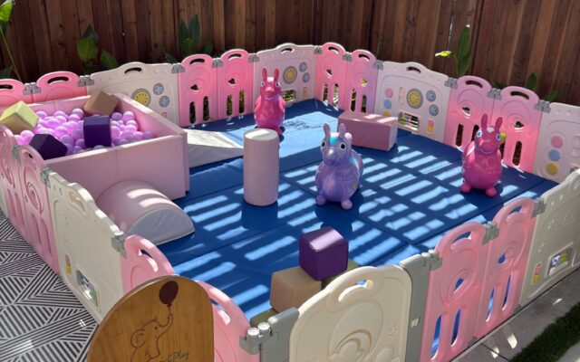 Colorful plastic playpen with toys in a sunny room.