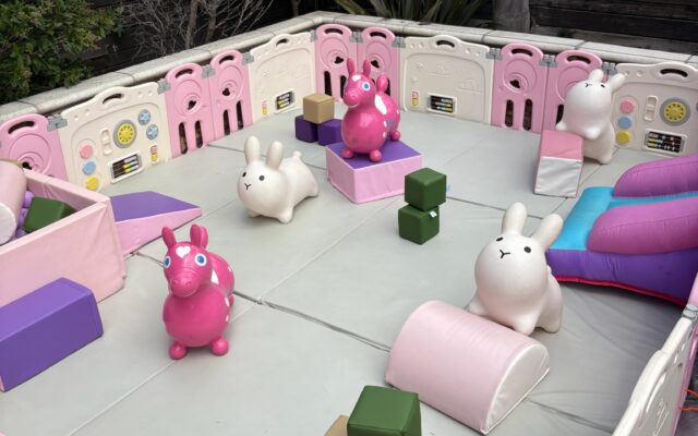 Colorful inflatable animals in a fenced play area with soft blocks.